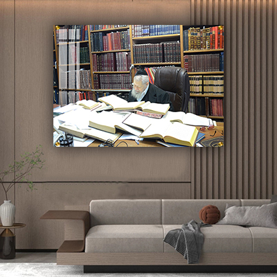 1528 – תמונה של הרב עובדיה יוסף לומד תורה בחדרו על רקע מלא ספרים