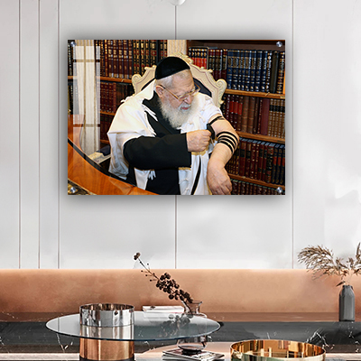 תמונה של הרב עובדיה יוסף עטוף בטלית ומניח תפילין בחדרו