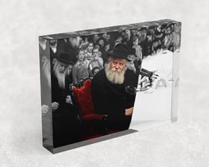 320 – תמונה של הרבי מחייך בהתוועדות ויושב על כיסא אדום